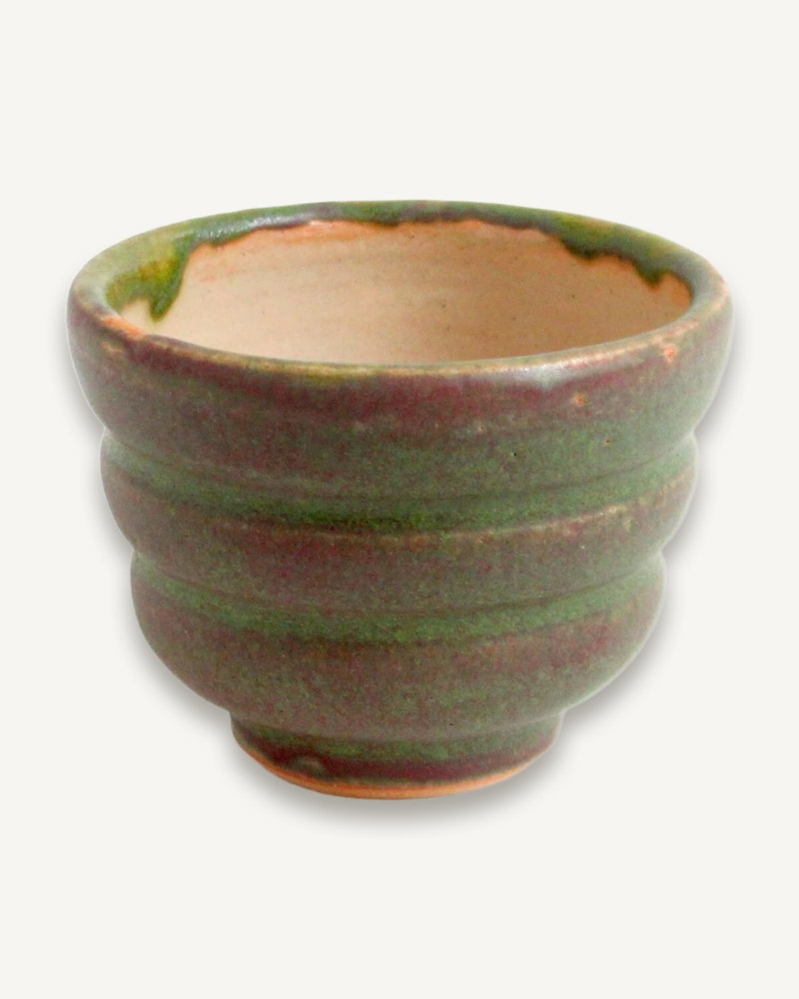 Thrown white stoneware cup with thick ridged walls in mossy green and burgundy, cream glaze visible inside rim.