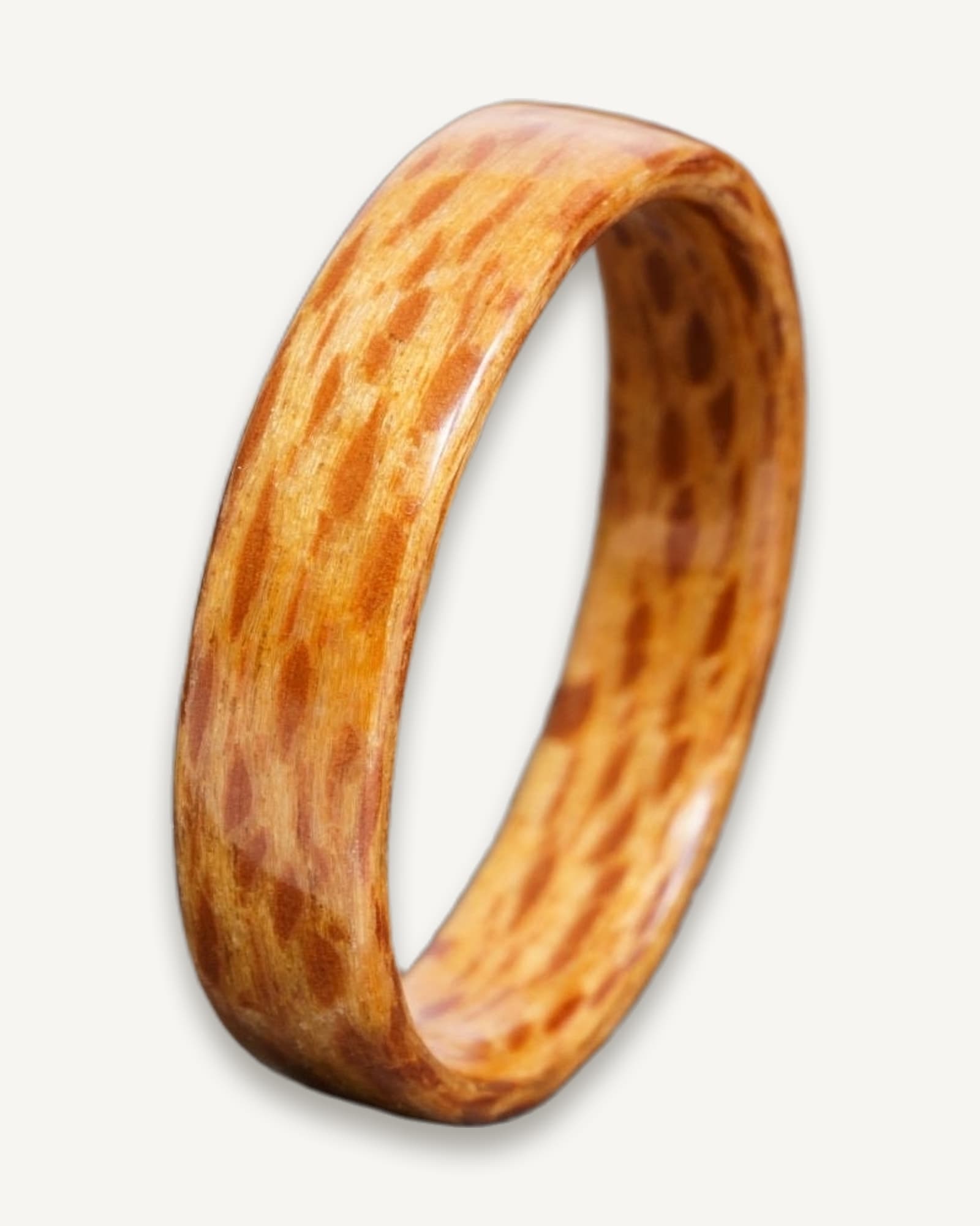 Polished bentwood ring with warm honey and reddish-brown grain, showing flecked pattern throughout.