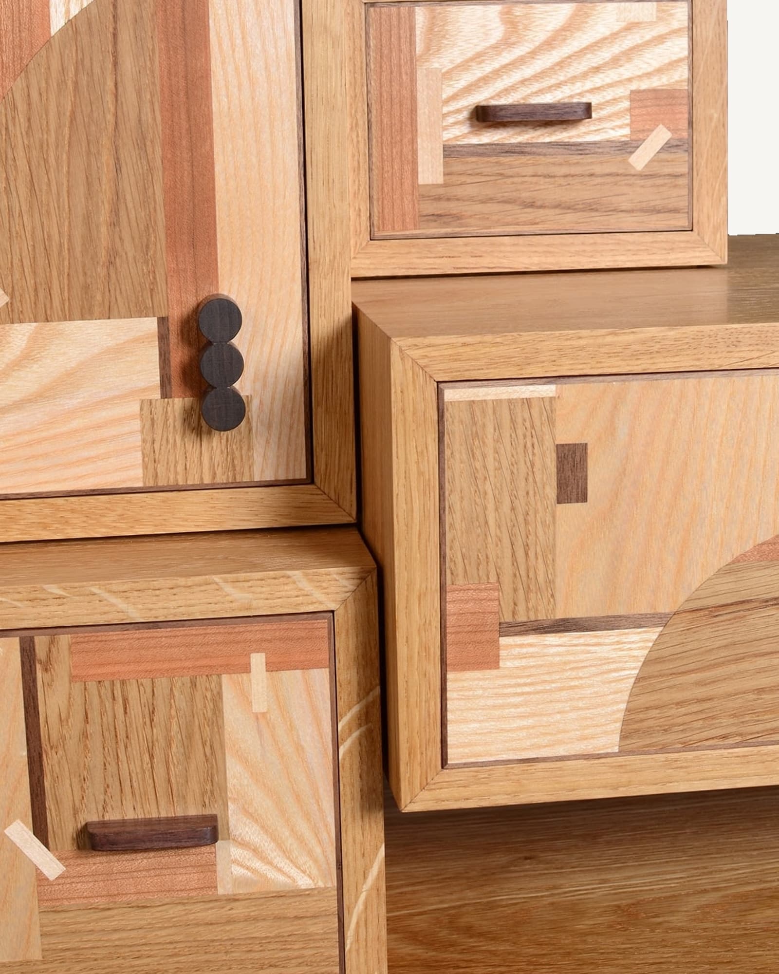 Oak console table with stacked geometric marquetry panels in contrasting wood tones, featuring dark spherical knob and