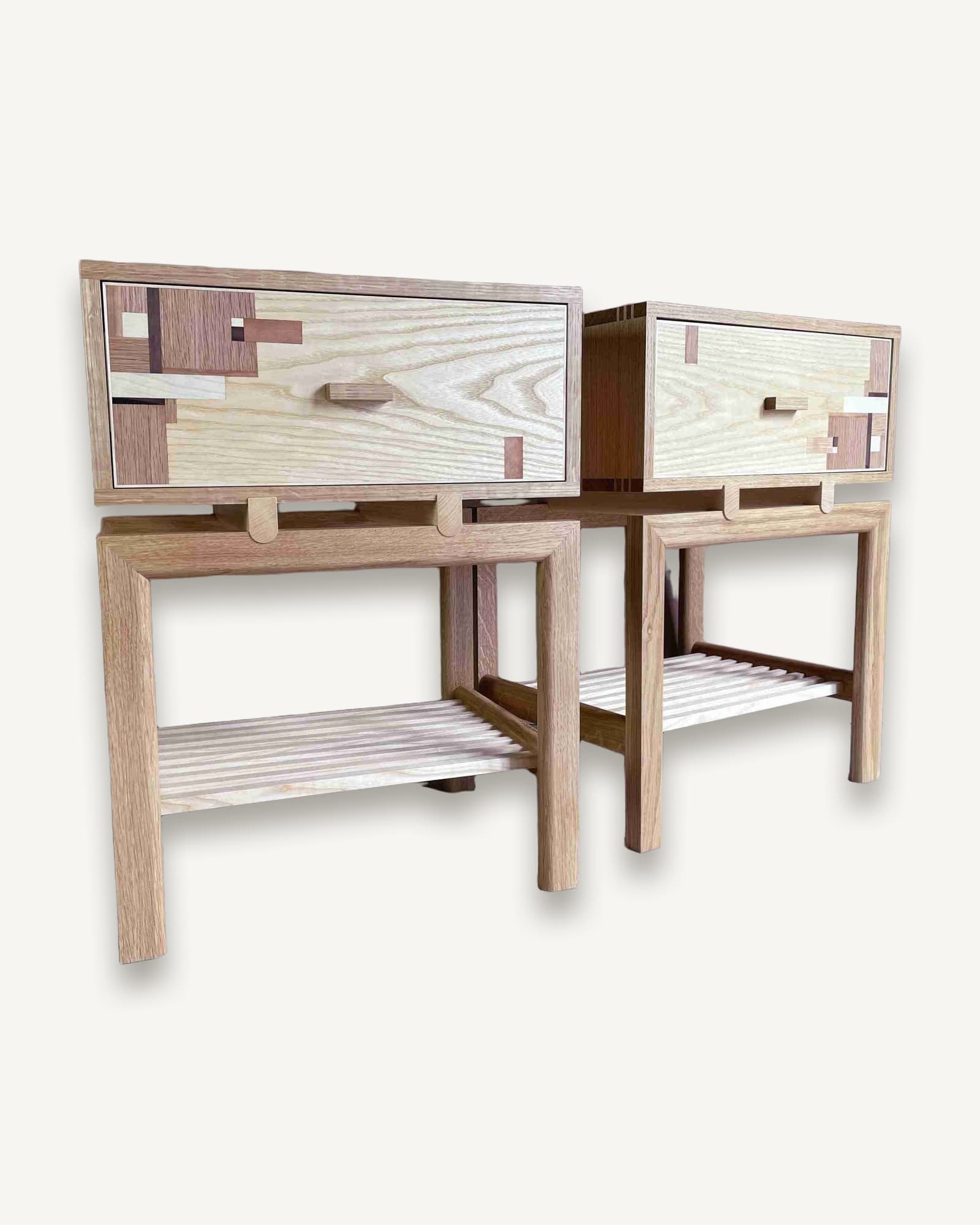Pair of wooden bedside tables with light ash frames and shelves, topped with darker wood drawers featuring geometric