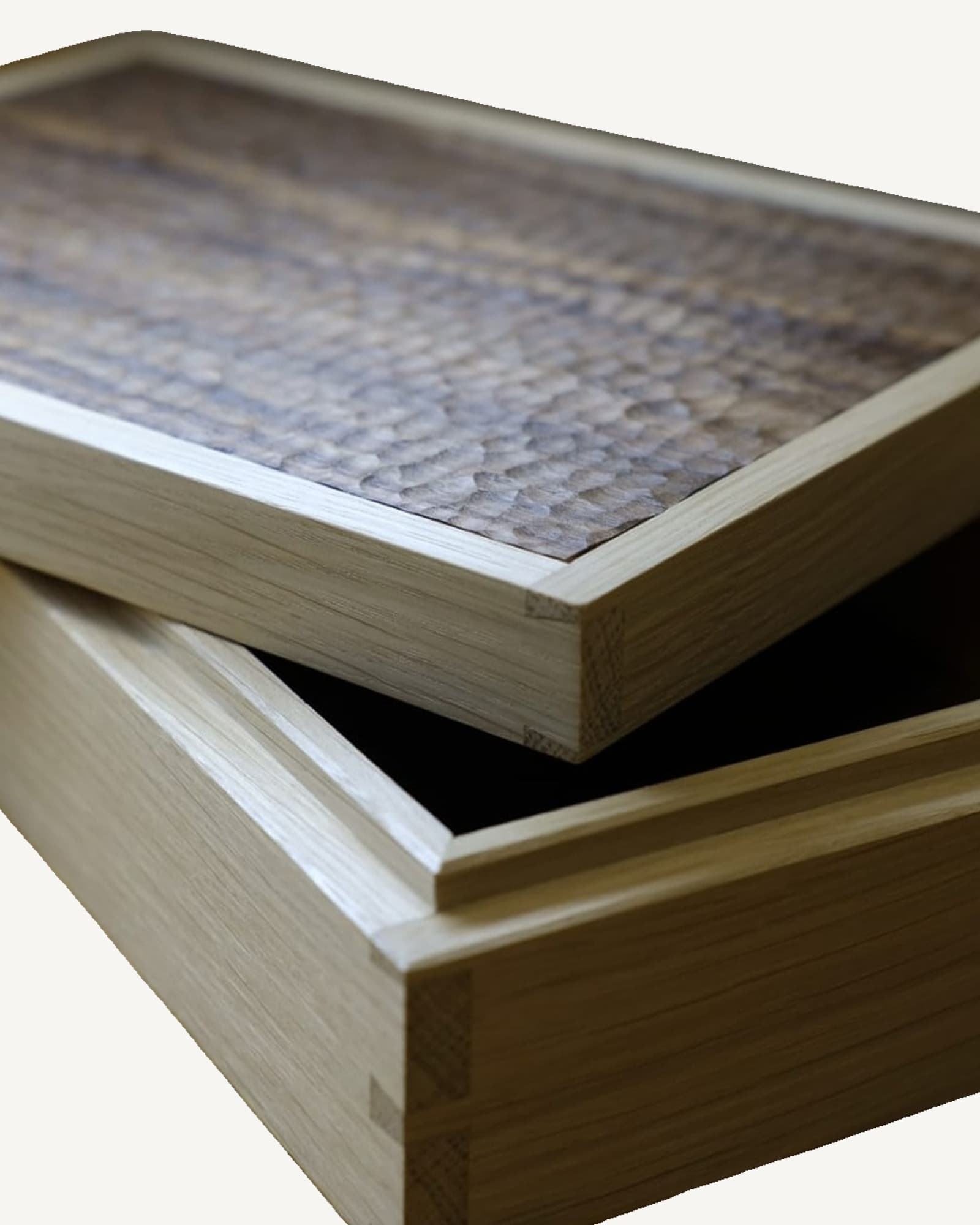 Stacked oak boxes with pale wood frames and white paper mounts, top box displaying hand-carved walnut lid with textured