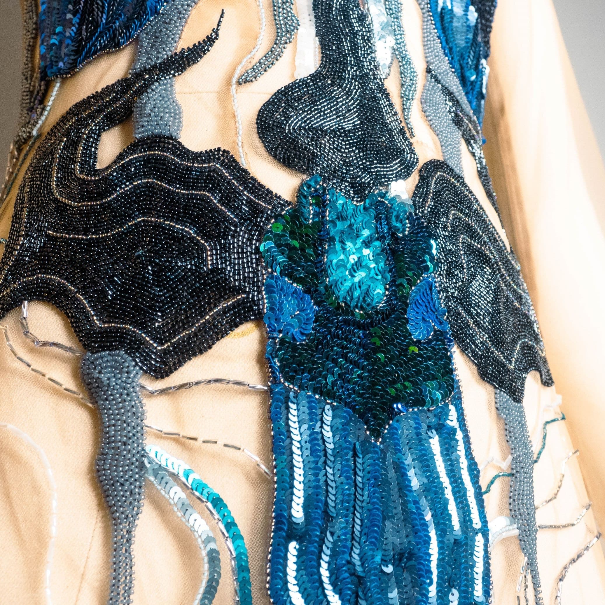 Close view of a teal sequinned orchid embroidered onto the sheer bodice of the dress