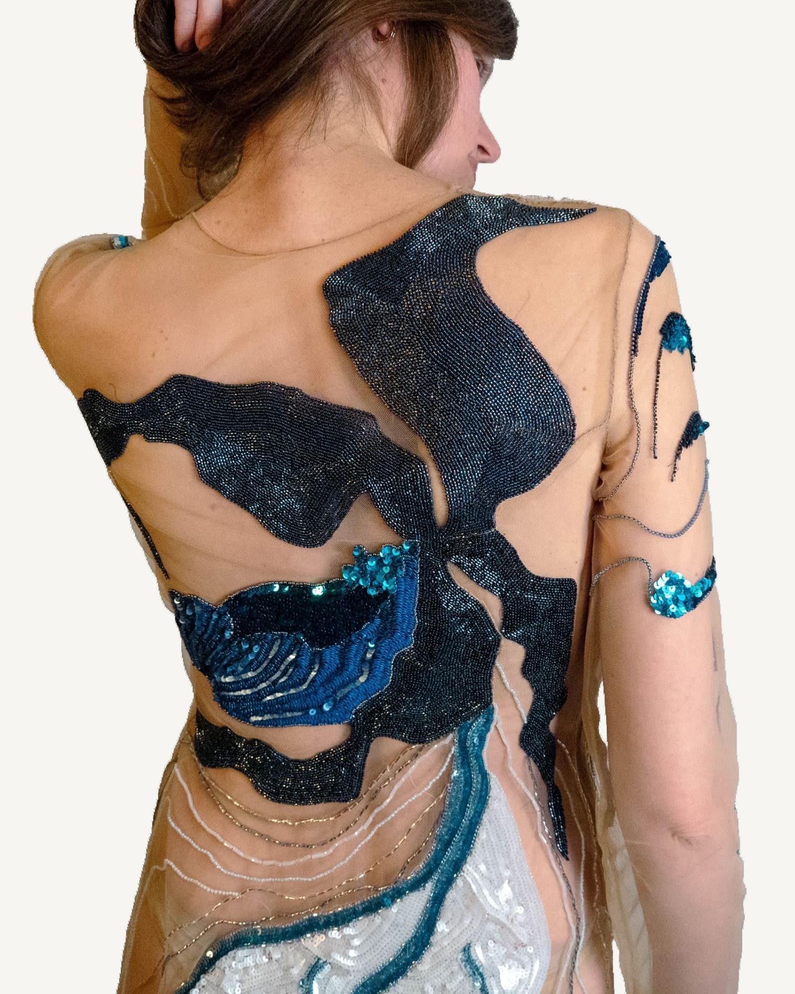 Sheer couture dress worn by a model, hand-embroidered with blue and teal Lady Slipper orchids across the body