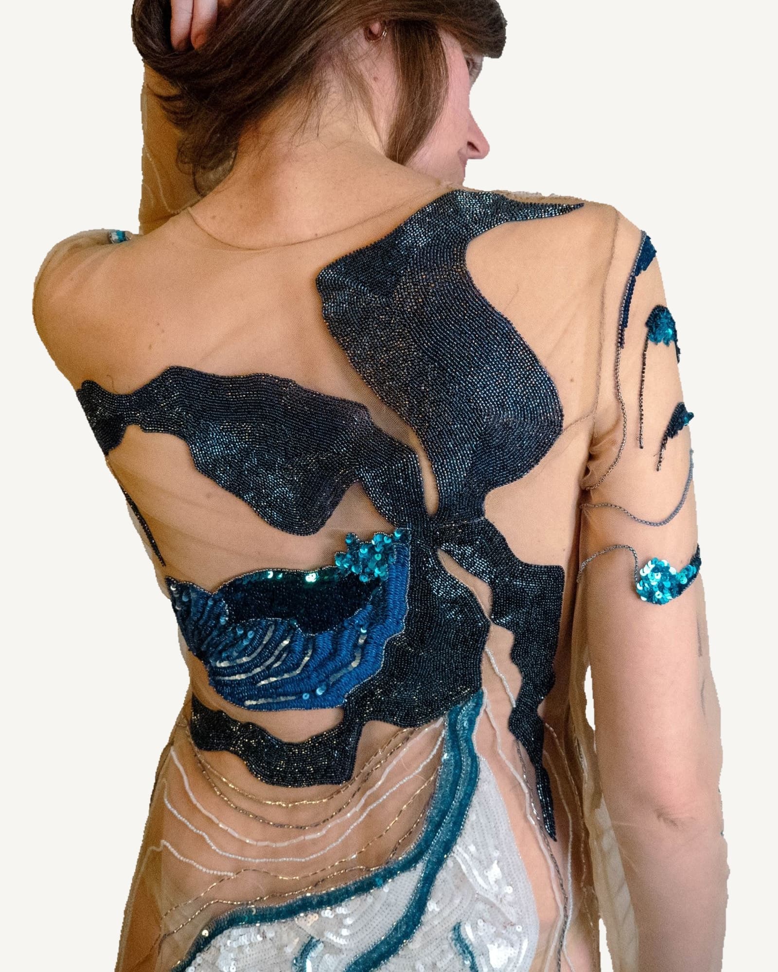 Sheer couture dress worn by a model, hand-embroidered with blue and teal Lady Slipper orchids across the body