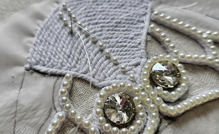Detail of pearl setting on the shoe: seed pearls seated on cords over pale fabric