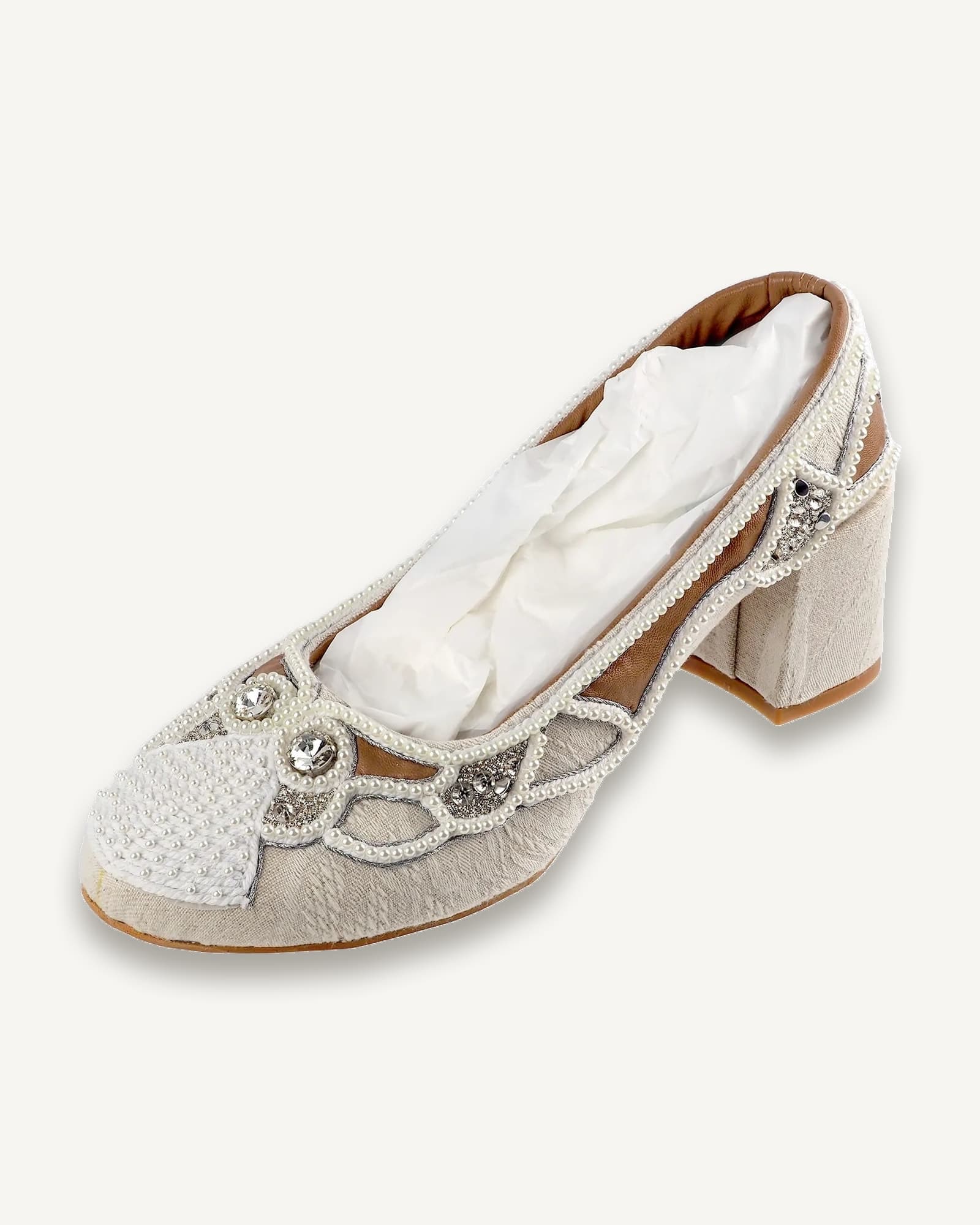 A pair of ivory shoes covered in Russian pearl setting embroidery, displayed on a clear plinth