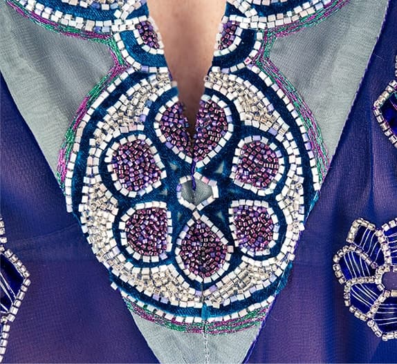 Close view of a solar motif embroidered in beads and pearls on purple chiffon