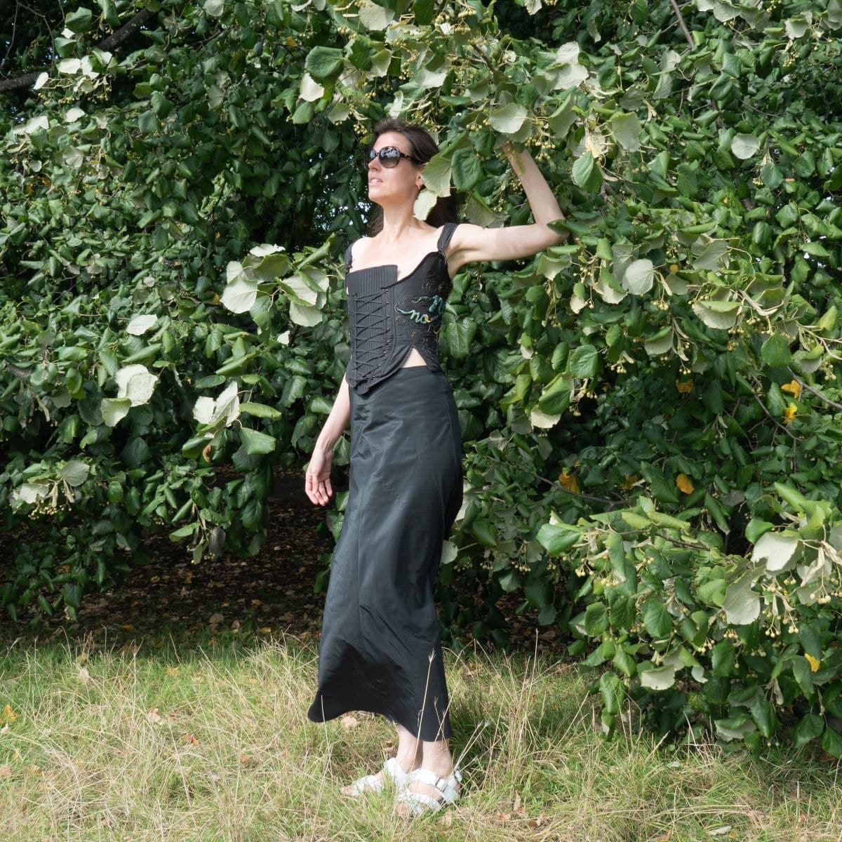 The corset worn as a full look with a long black skirt, photographed outdoors