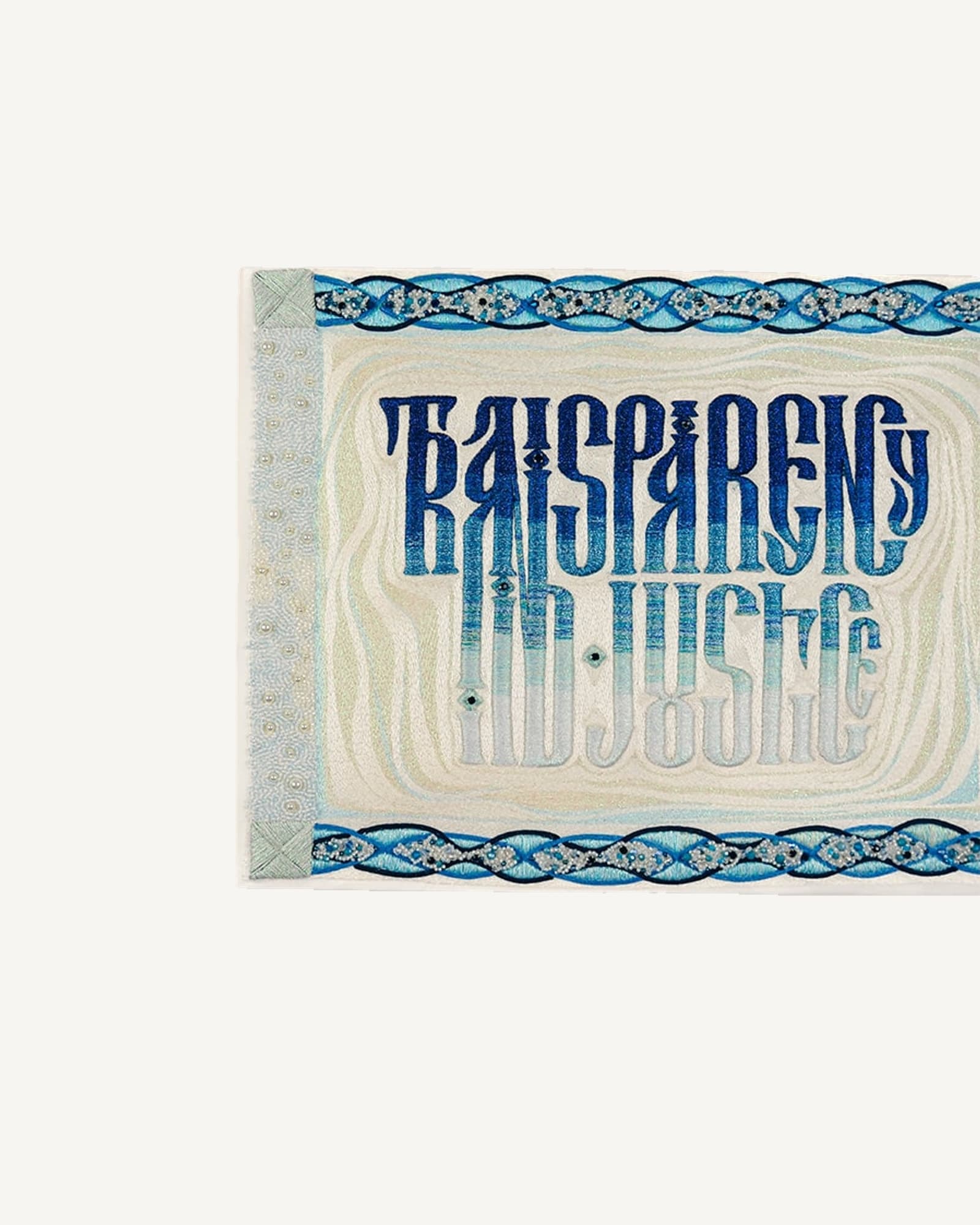 Framed embroidered panel hung on a white wall, the words worked in blue vyaz lettering within a patterned border