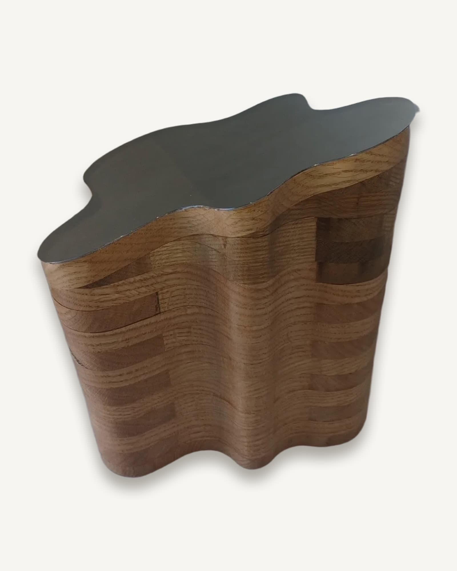 An urn built up in stacked waves of English oak, topped with a polished stainless steel lid.