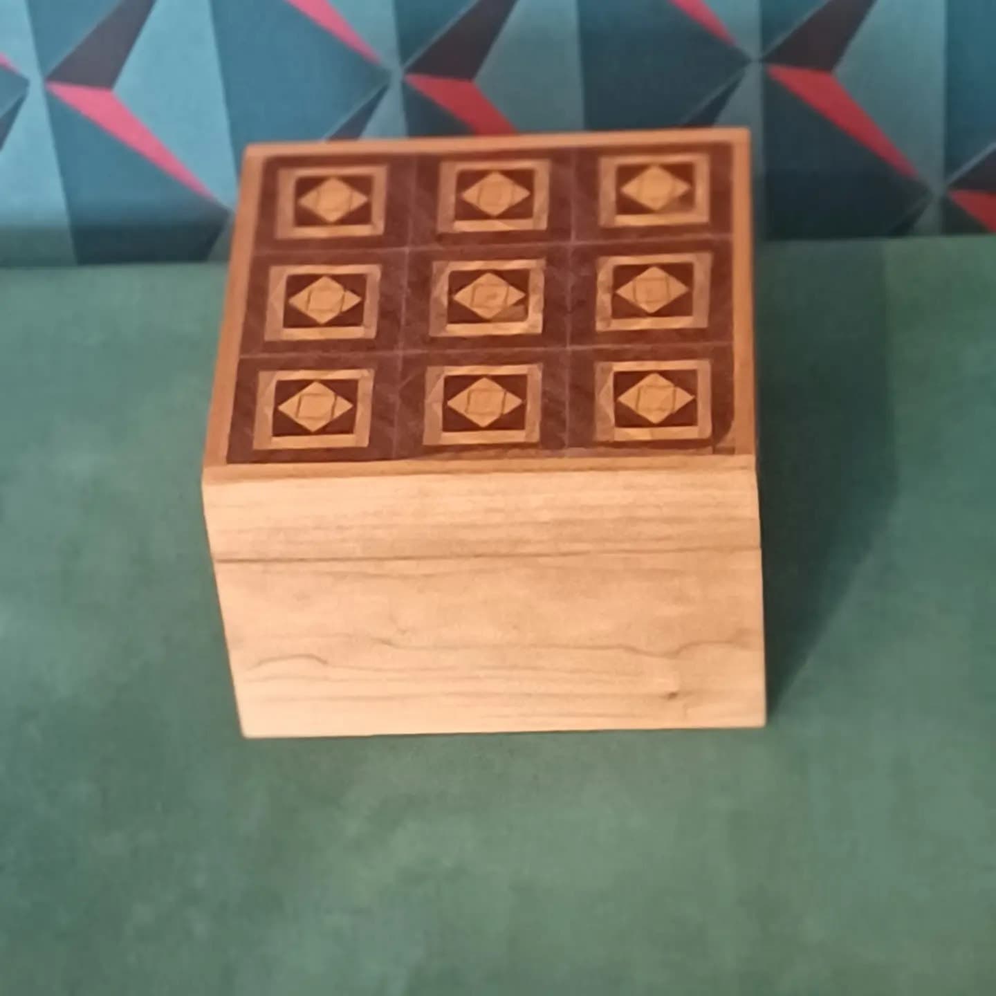 The box from above on a green cloth, the nine-panel lid in walnut and iroko.