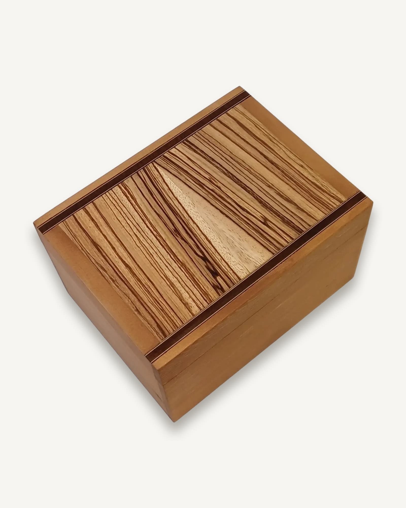 A cherry box with a zebrano lid, the stripes running on the diagonal and split down the middle by a wedge of pale wood.