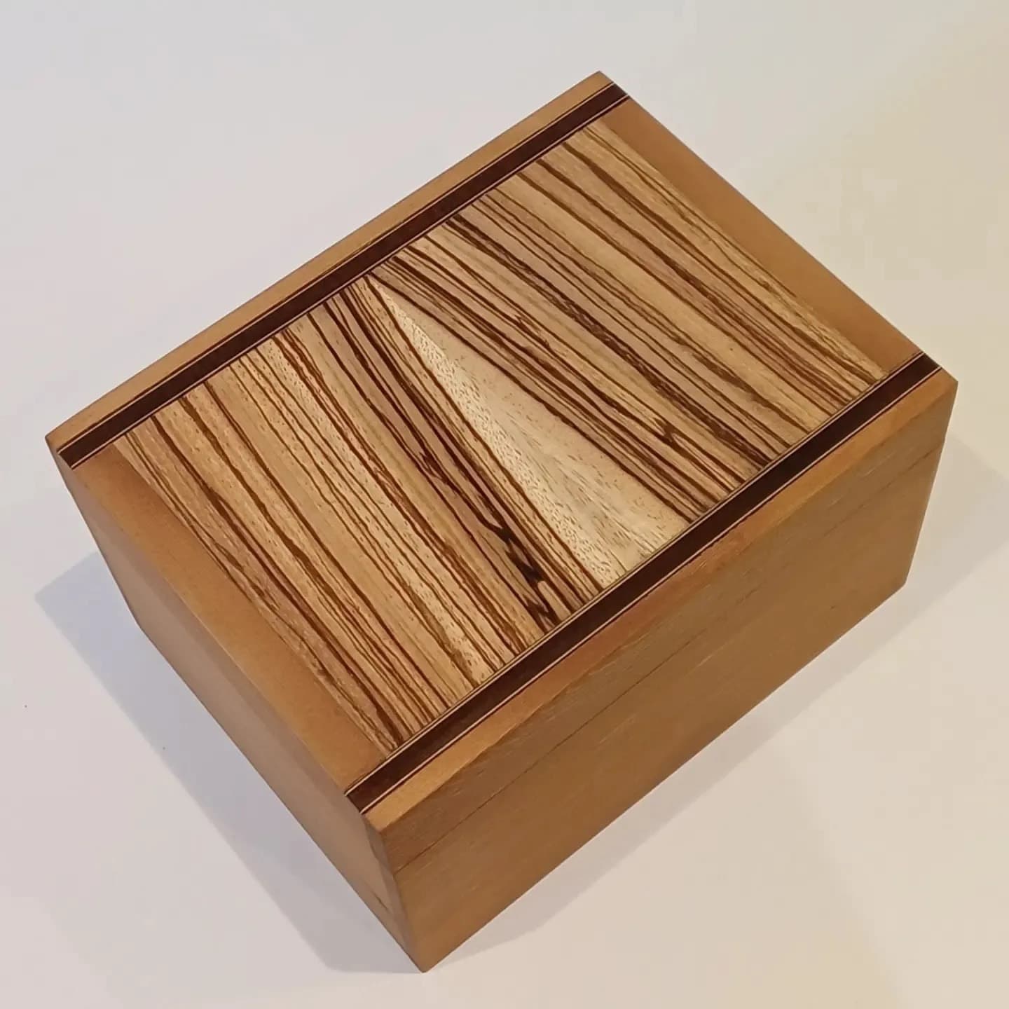The same box from the other side, the striped lid catching the light along its edge.