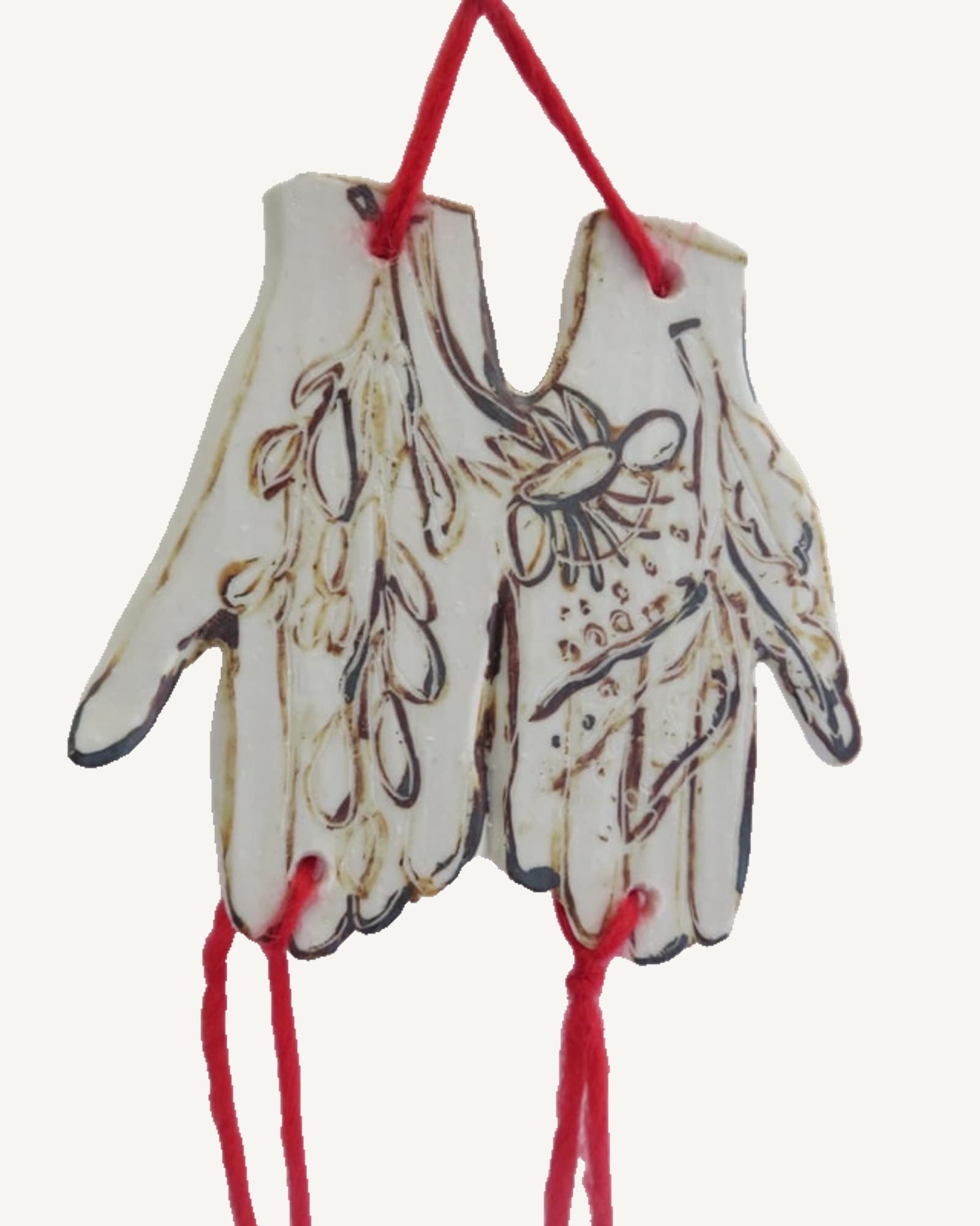 A porcelain wall piece of two hands, hung on red Welsh wool