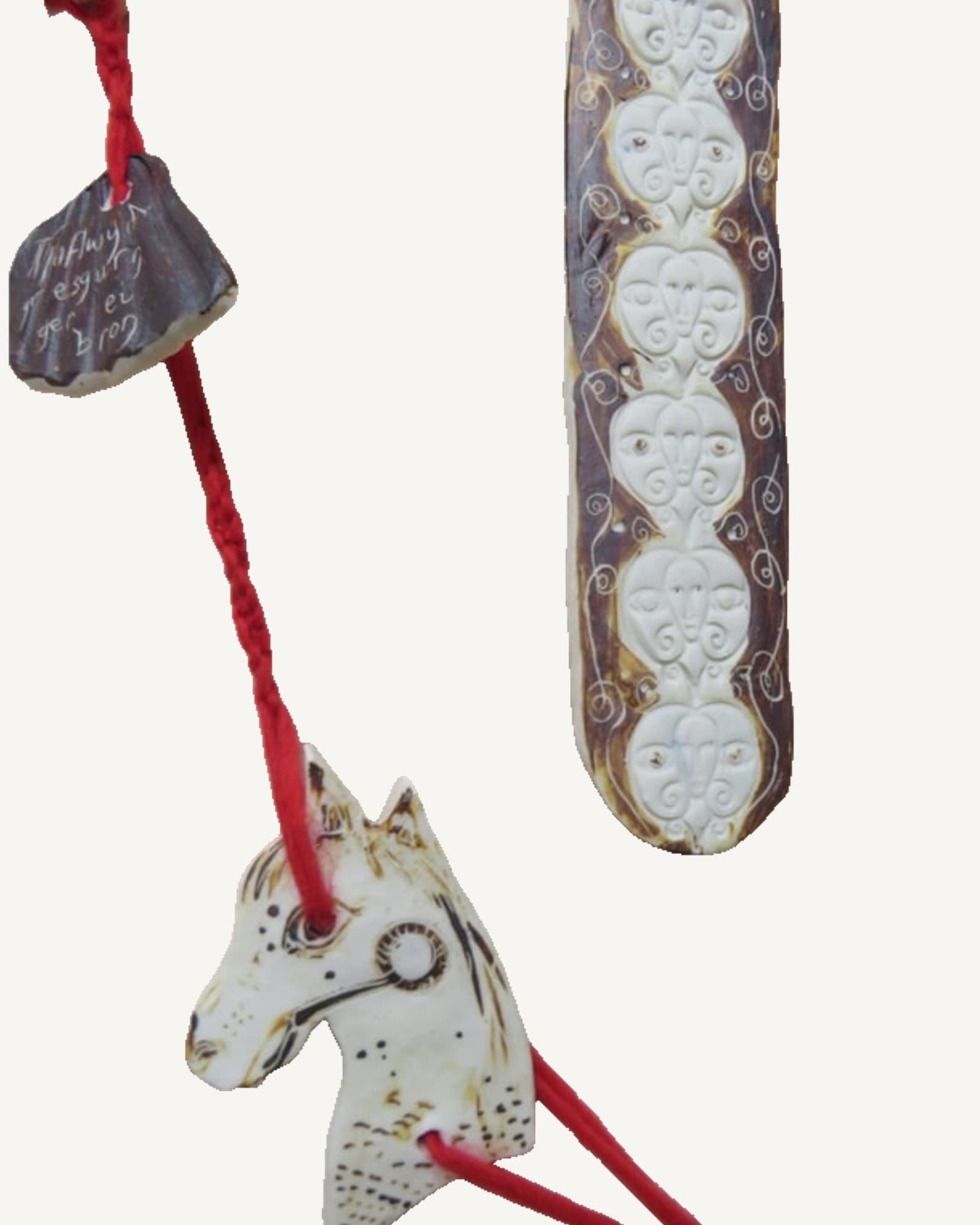 Porcelain wall pieces from Merched y Mabinogi hung together on red wool