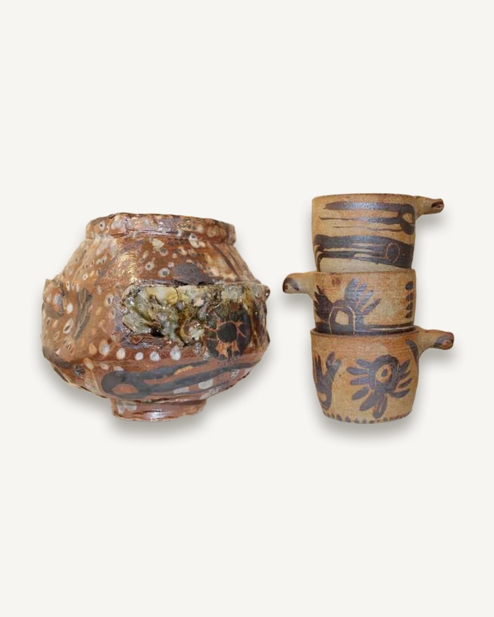 A wood-fired ceramic pot and two handled cups with slip decoration
