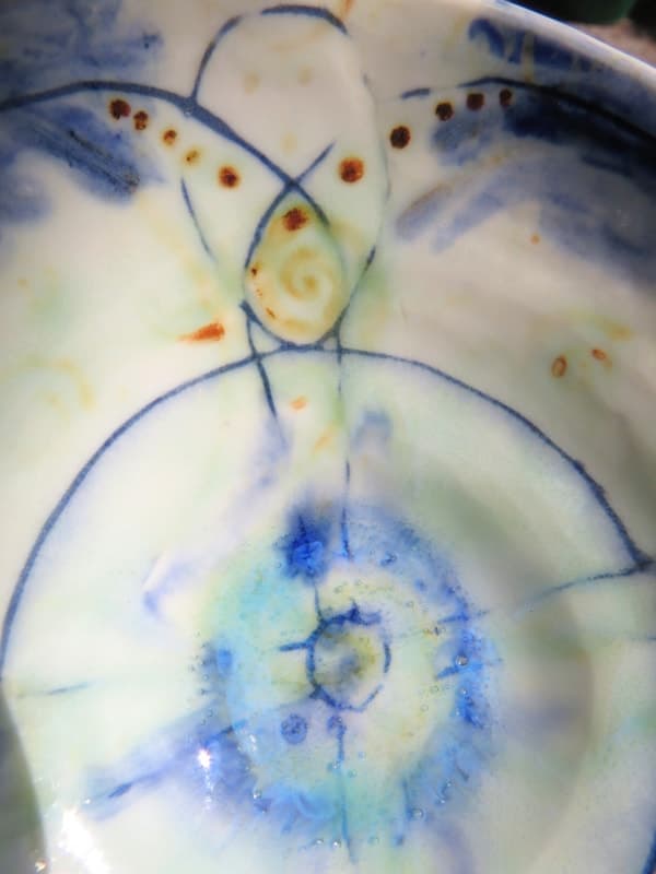 Close detail of blue linear decoration inside a pale ceramic bowl