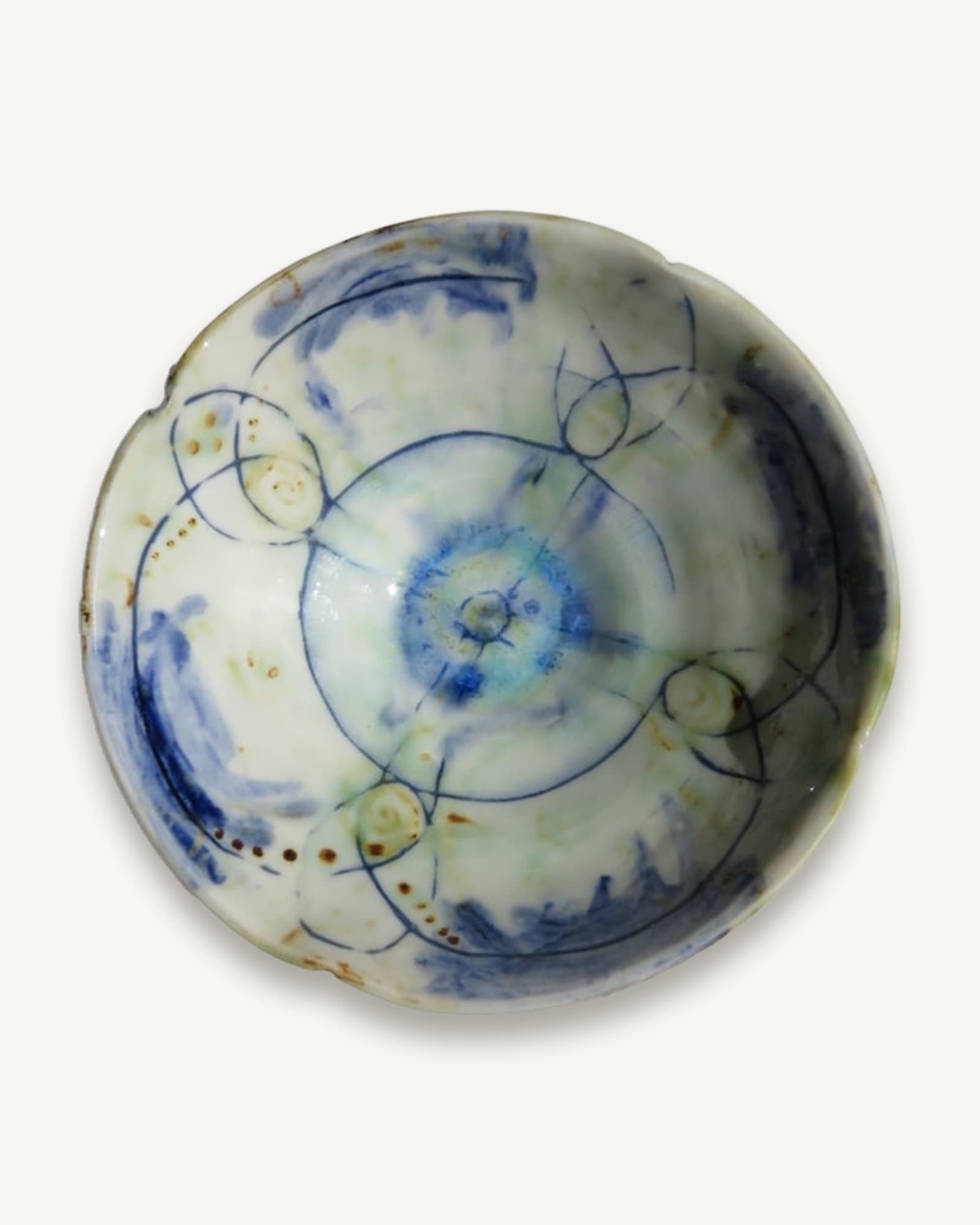 A pale ceramic bowl decorated inside with fine blue circles and arcs