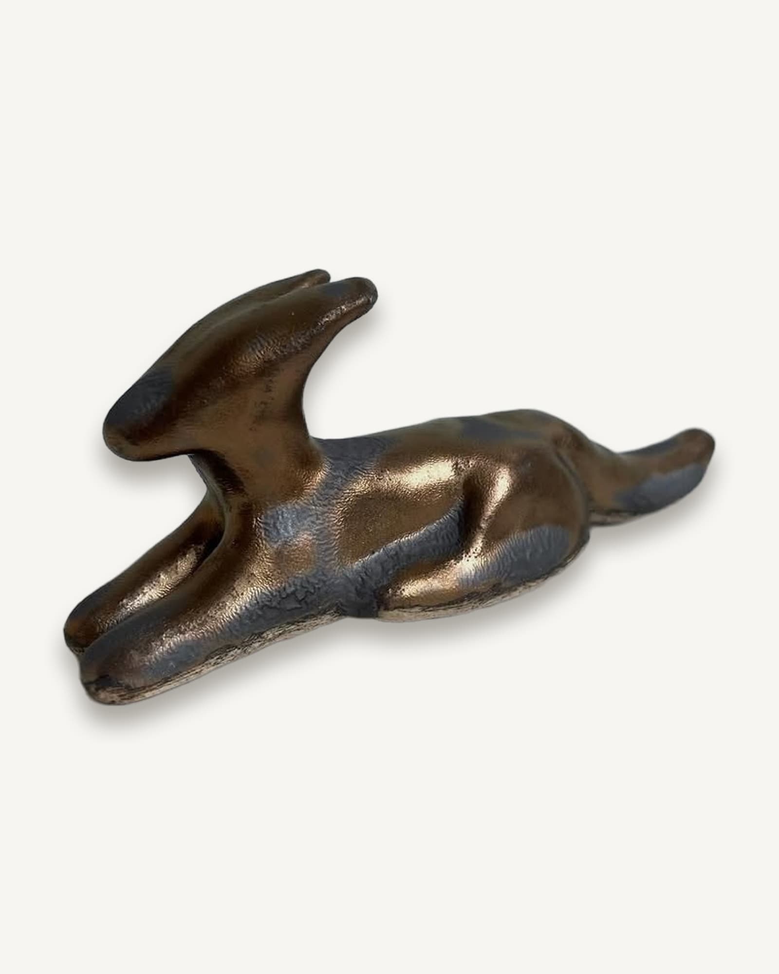 Bronze hound figurine in recumbent pose with stretched front legs, lifted head and extended tail