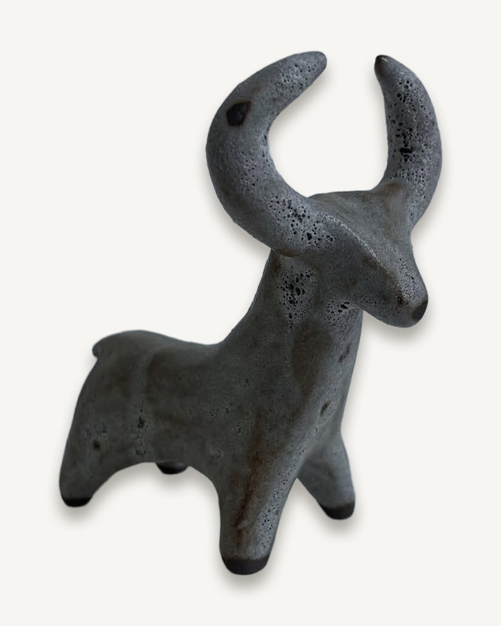 Standing black clay figure with swept-back crescent horns, grey volcanic glaze with pitted texture across the surface.