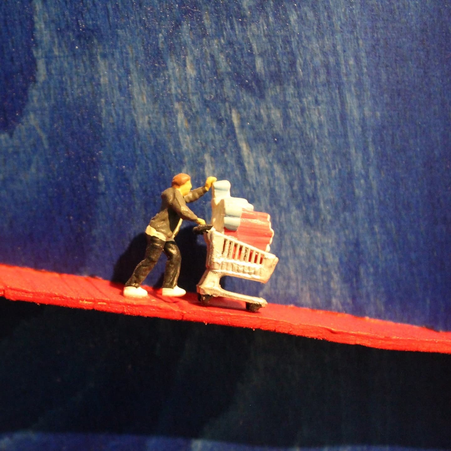 Model figure of a woman pushing a pram on the red spiral ledge of a deep blue turned vessel