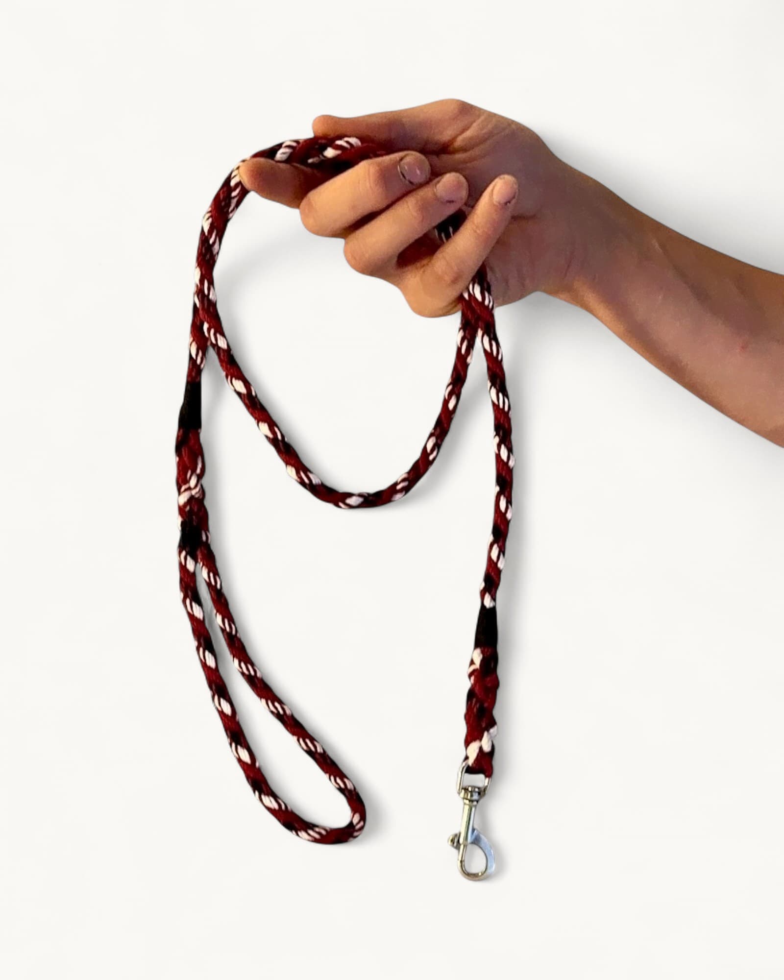 Hand-held red, white and black twisted rope leash with stainless-steel clip, displayed against white background.