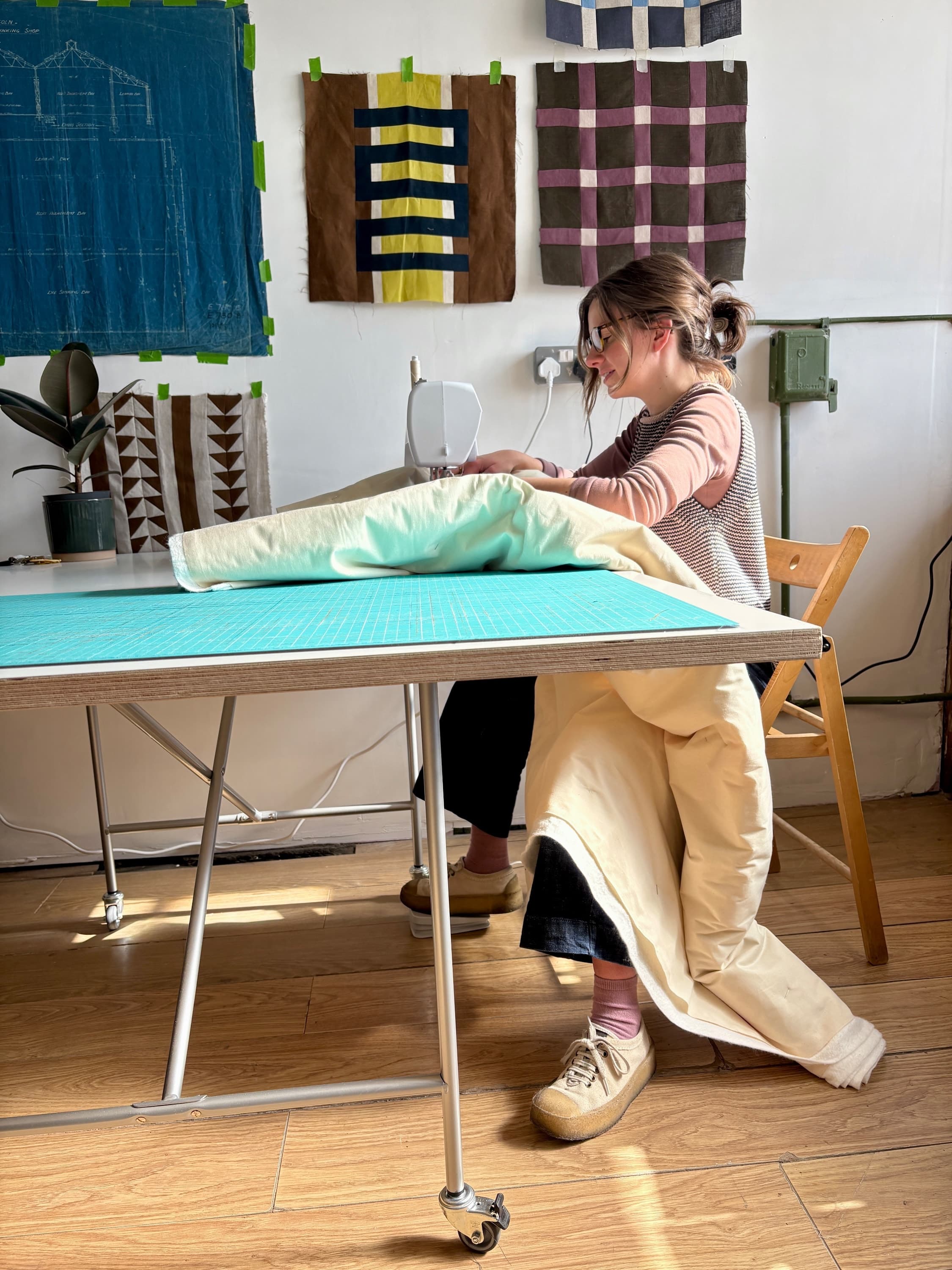 Maker at a work table with a turquoise cutting mat, holding cream and mint fabric