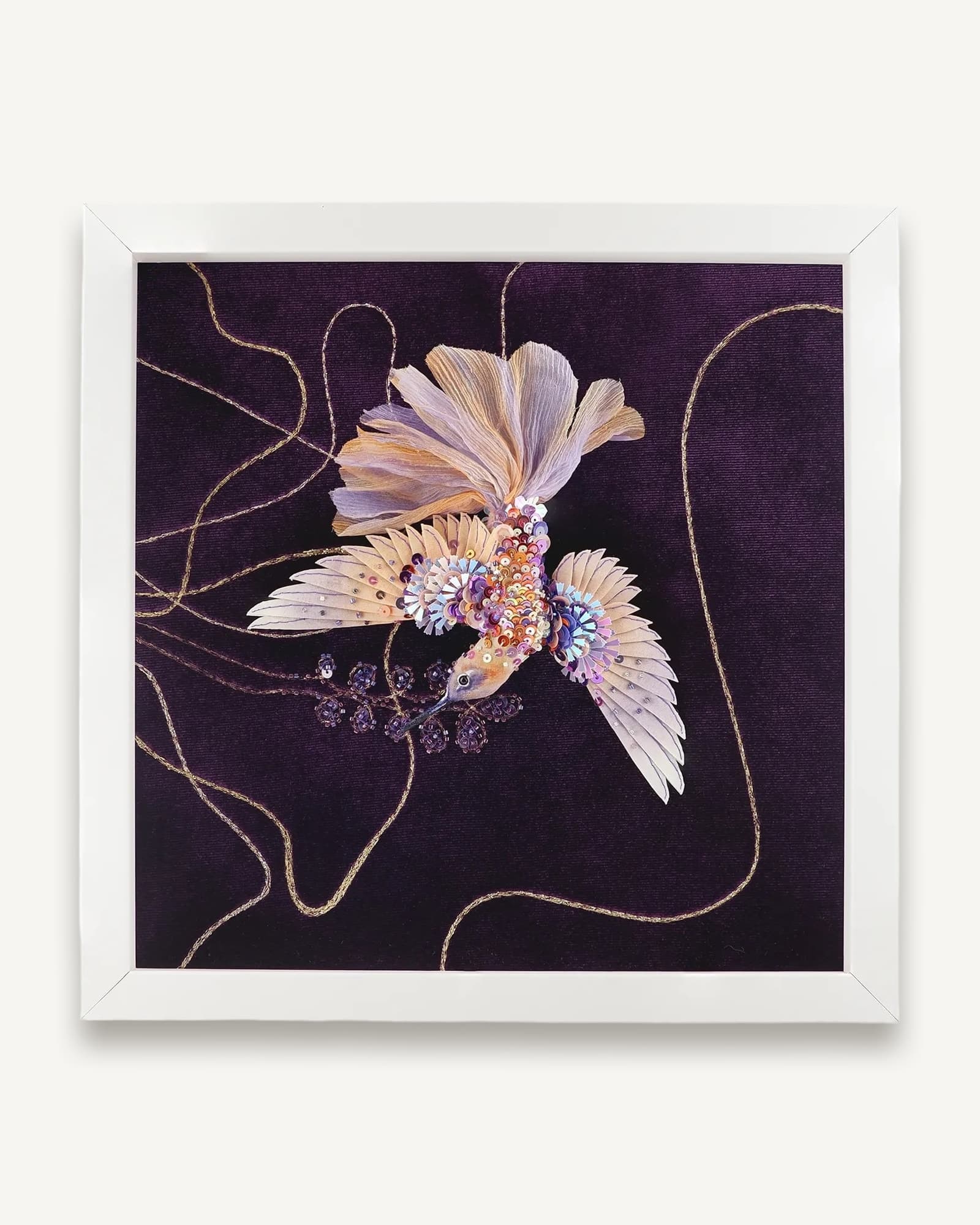 Framed textile artwork featuring a hummingbird with spread wings in cream and lavender, embellished with beads and sequins