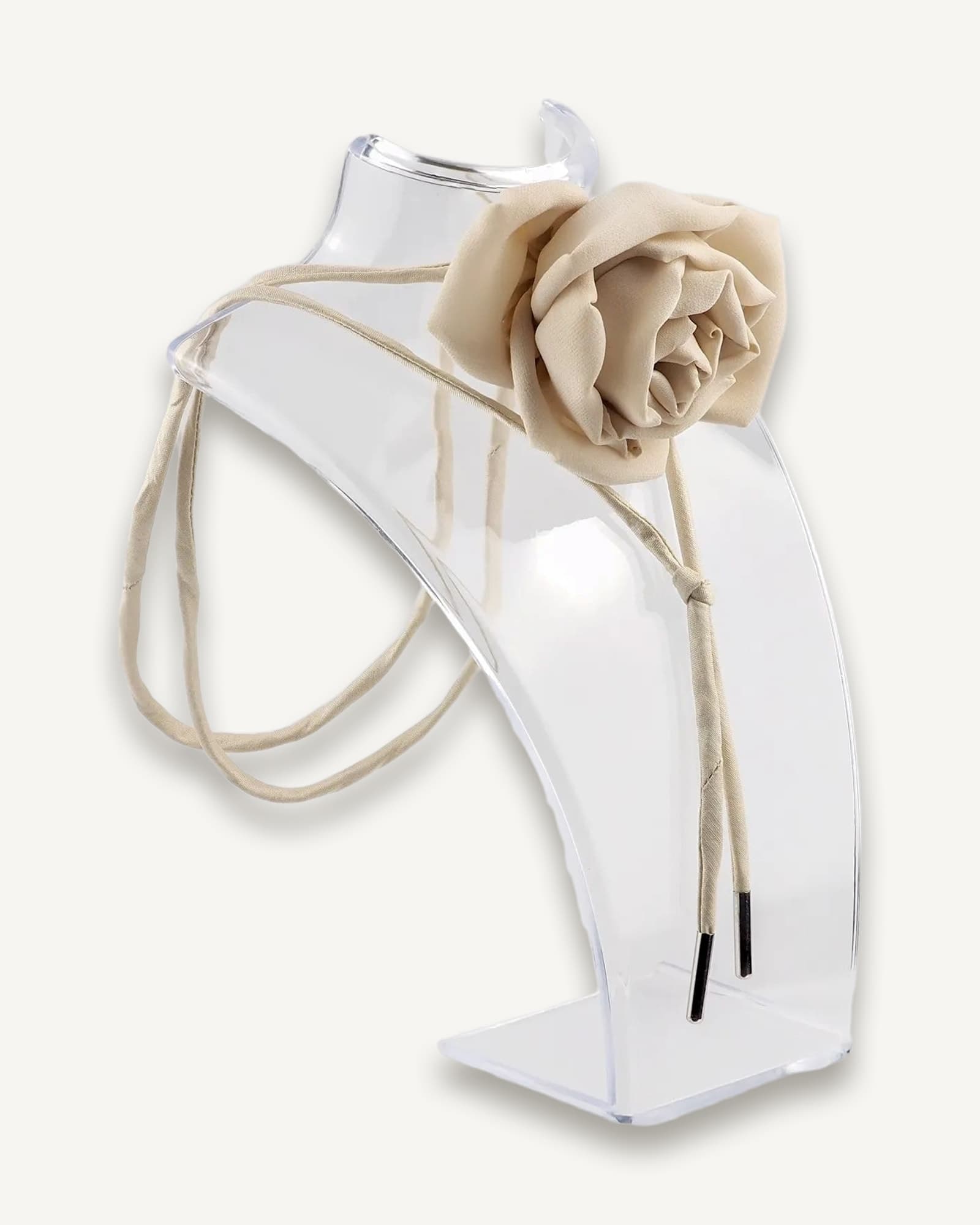 Nude silk rose choker by Ksenia Semirova displayed on a clear acrylic stand. This handcrafted accessory features a nude rose centerpiece, nude dupioni silk lace, and nickel-free metal ends, highlighting elegant design and artisanal craftsmanship.