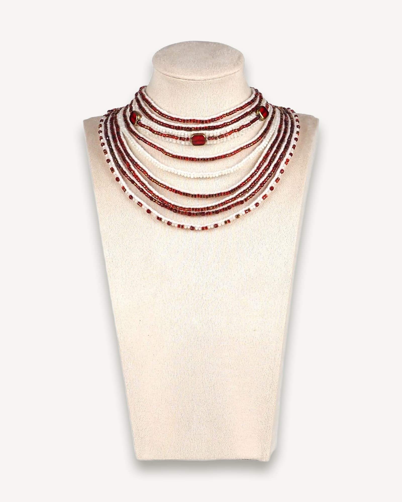 Handmade red and white multi-strand necklace with glass beads, mother of pearl beads, and larger gold-edged round beads, displayed on a mannequin bust