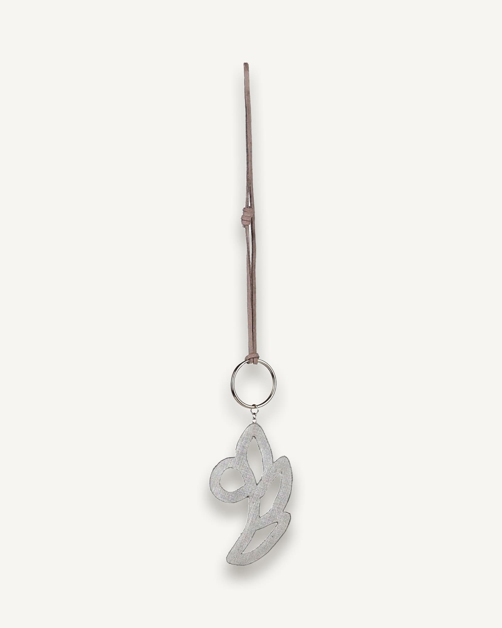 Back view of white and silver floral bag charm, finished with faux leather lining and suede strap