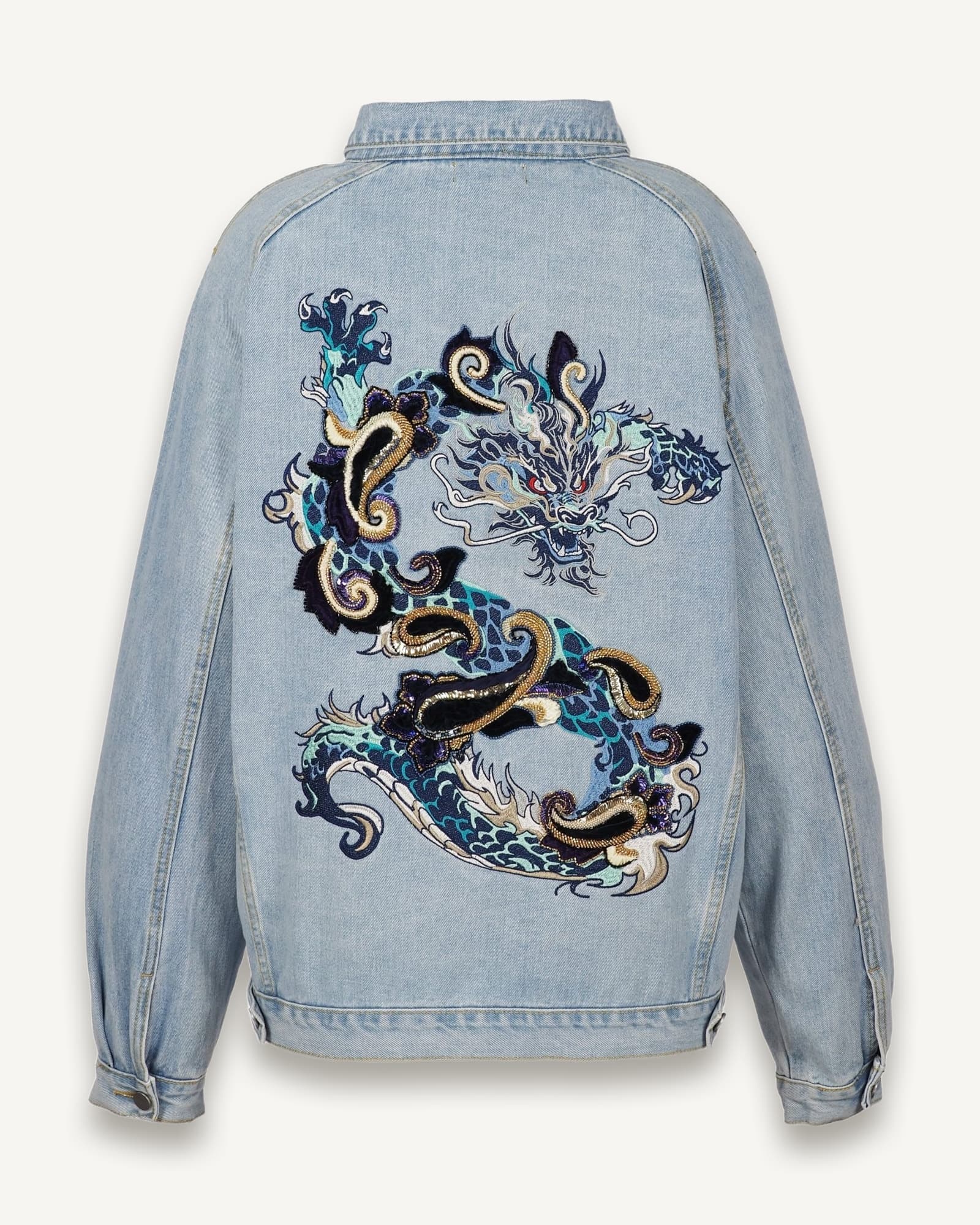 Back view of oversized light blue denim jacket featuring intricate dragon embroidery in blue, gold, and white threads, created with machine and hand embroidery techniques, on a white background.