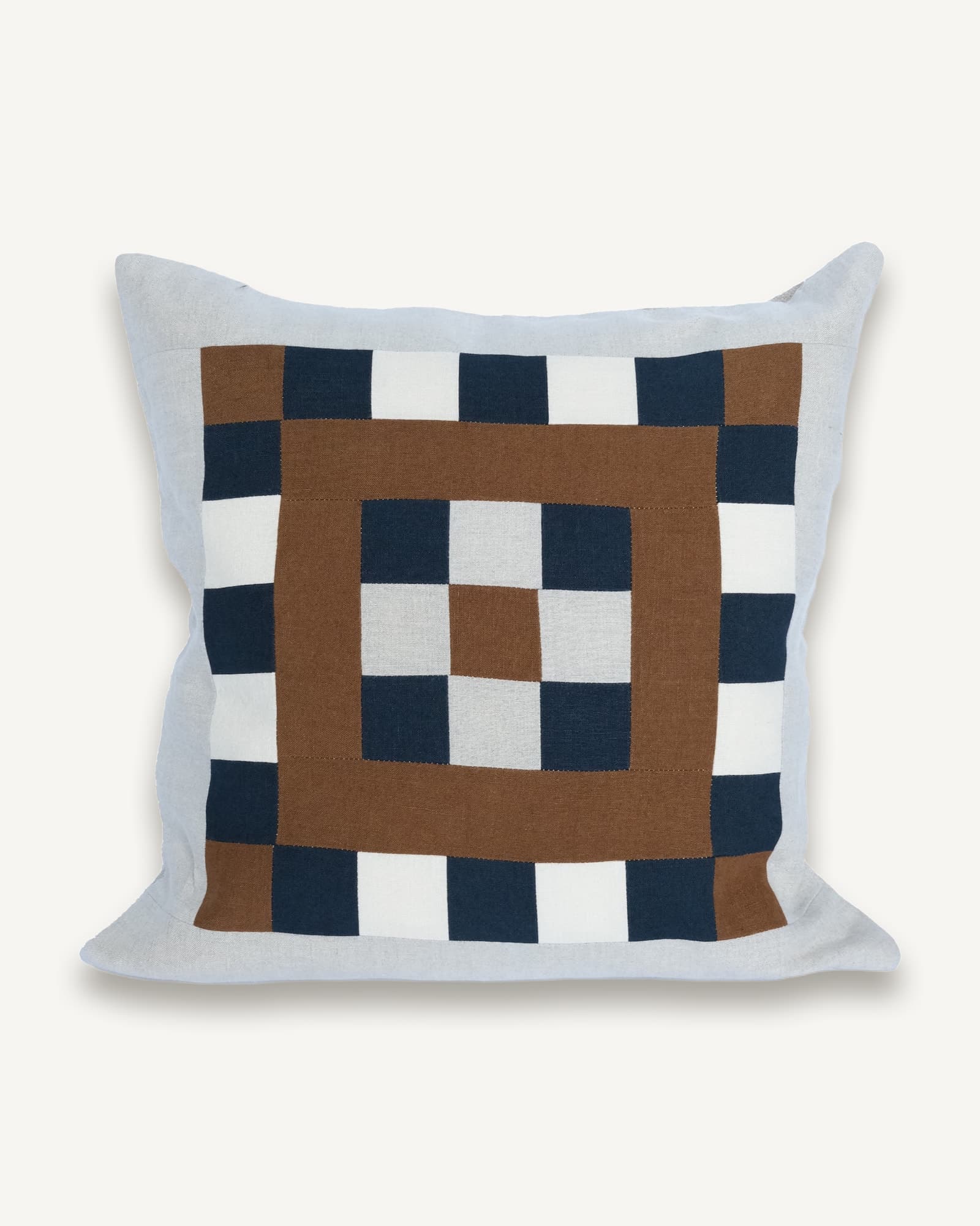 Pale blue linen cushion with a patchwork mosaic of brown, navy and cream blocks across the front