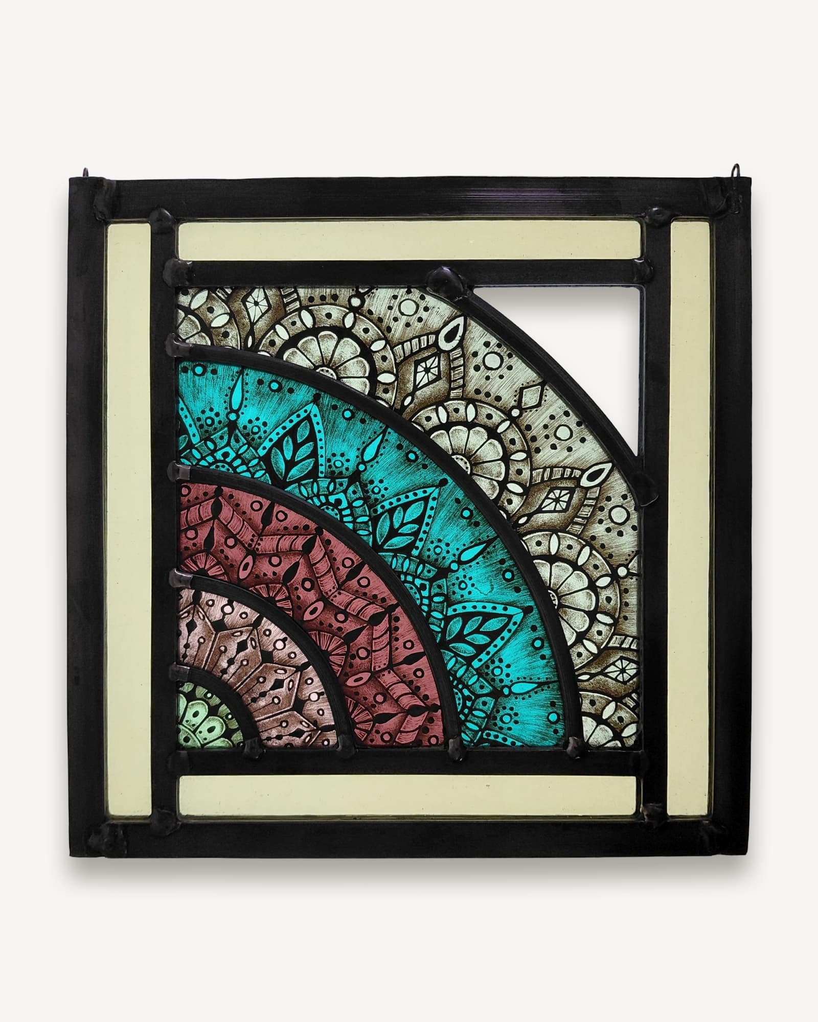Stained glass panel with black frame and cream borders, showing a quarter mandala design of concentric arcs in turquoise