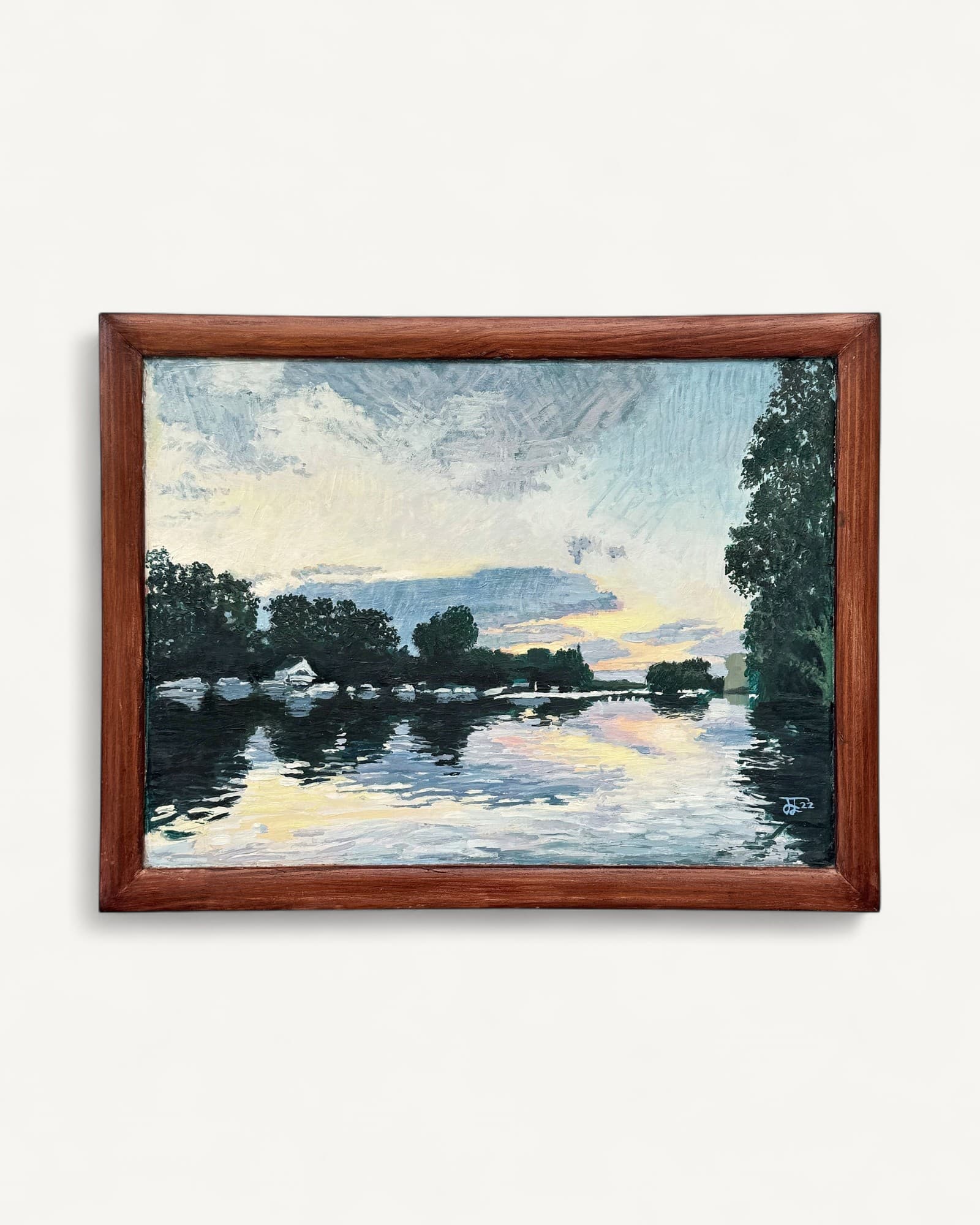 Oil painting in dark wood frame depicting river landscape at sunset, with dark green trees flanking water reflections in