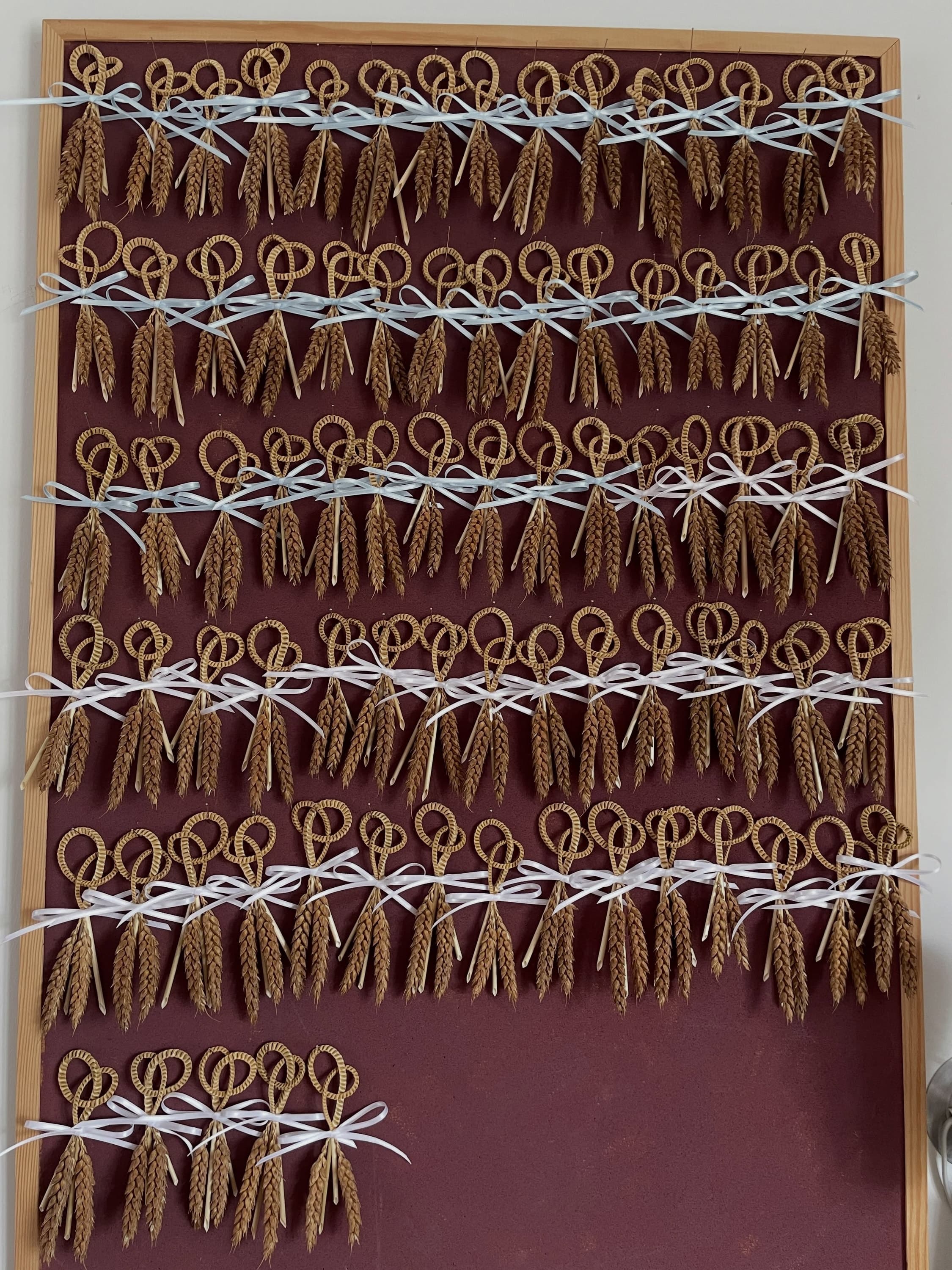 Rows of straw Lover's Knots tied with blue and white ribbon, made as wedding favours