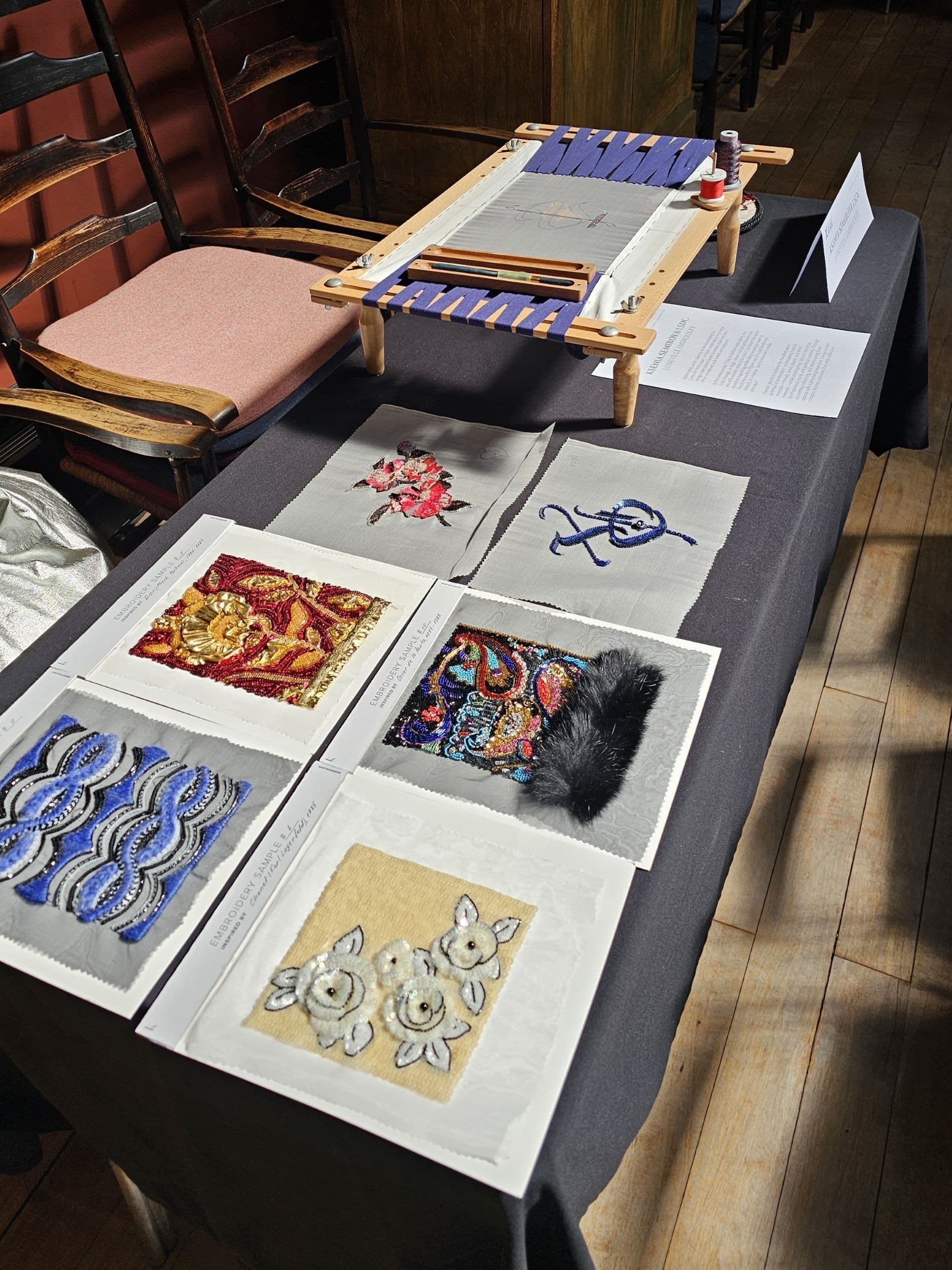 Display of embroidered textile samples showing red, blue and gold beadwork, floral and geometric patterns