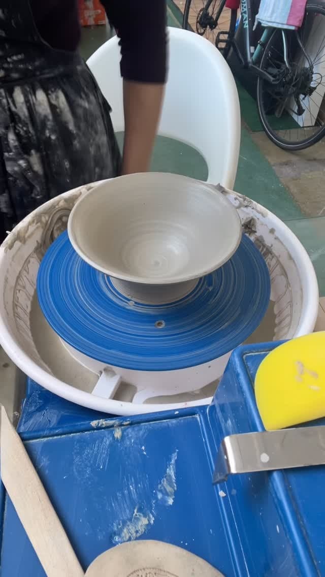 Ceramic bowls nested in white and blue containers, showing cream-colored interior and blue exterior surfaces with concentric