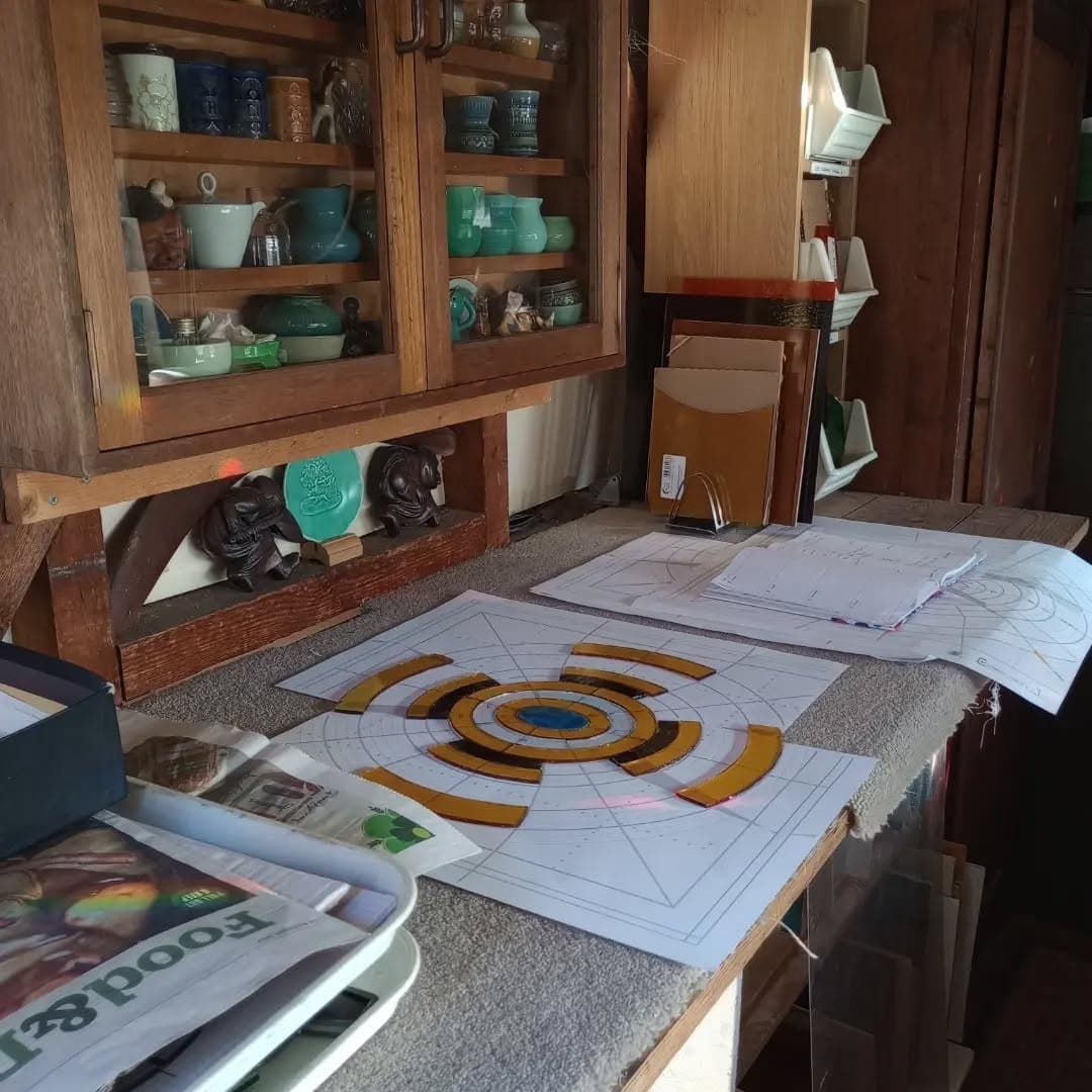 A part-built stained glass panel laid out on its paper cartoon on the workshop bench.