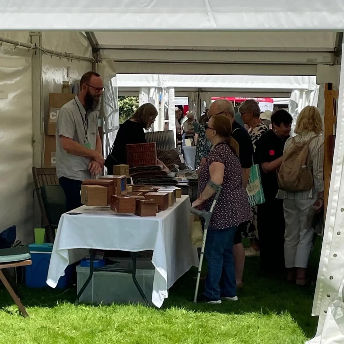 Alex Botes behind a table of his boxes at a craft fair, talking to visitors.