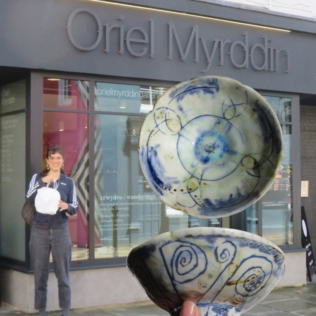 Bethan outside Oriel Myrddin gallery holding two of her decorated porcelain bowls