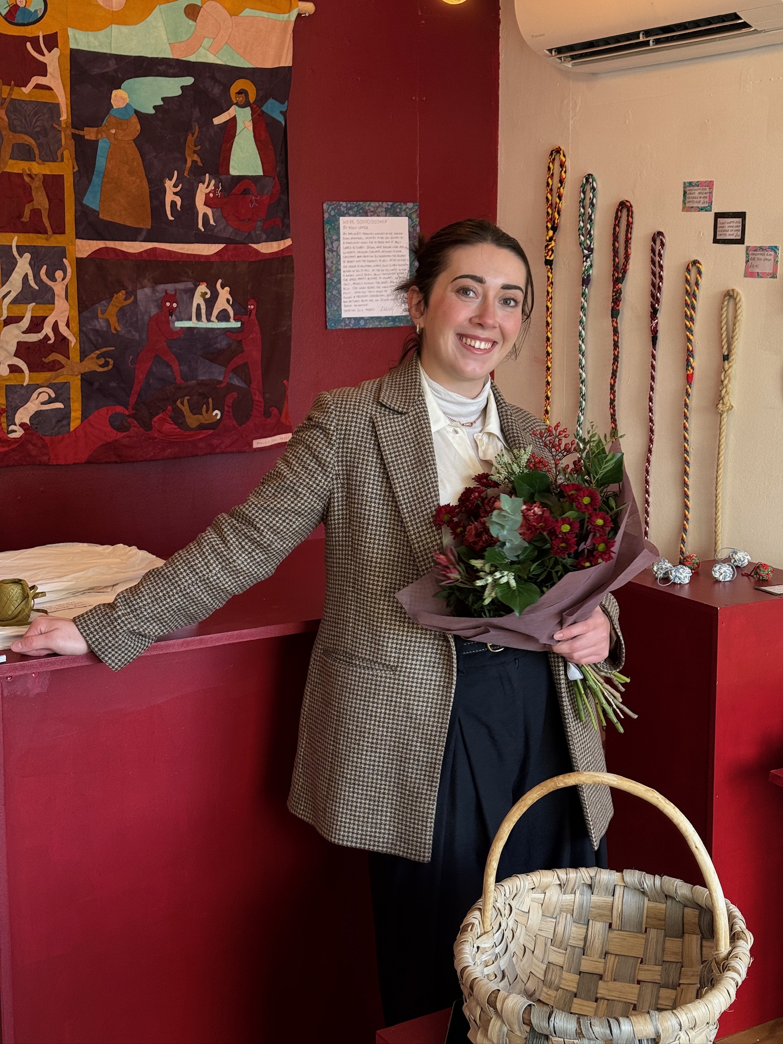 Rosie Thompson with a bouquet in The Haud pop-up shop, beside a wall of woven rope work