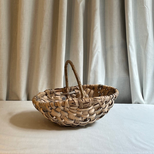Woven basket on a white surface with beige curtains in the background