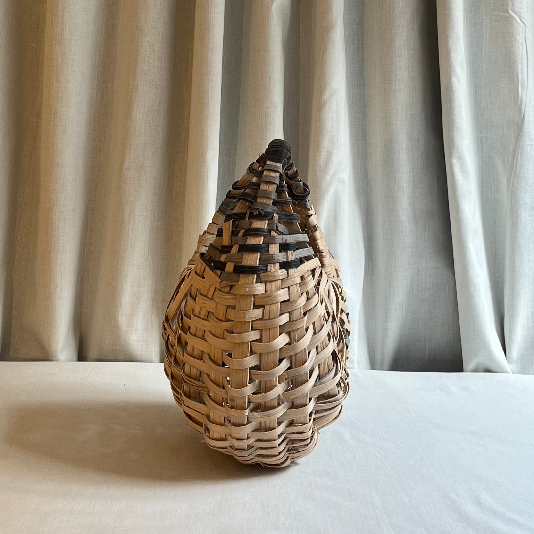 Woven basket on a white surface with a neutral curtain background