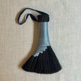 Load image into Gallery viewer, Decorative broom with black bristles and a colorful handle on a textured beige background

