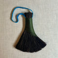 Load image into Gallery viewer, Decorative broom with black bristles and a colorful handle on a textured beige background
