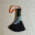 Load image into Gallery viewer, Decorative broom with black bristles and a colorful handle on a textured beige background
