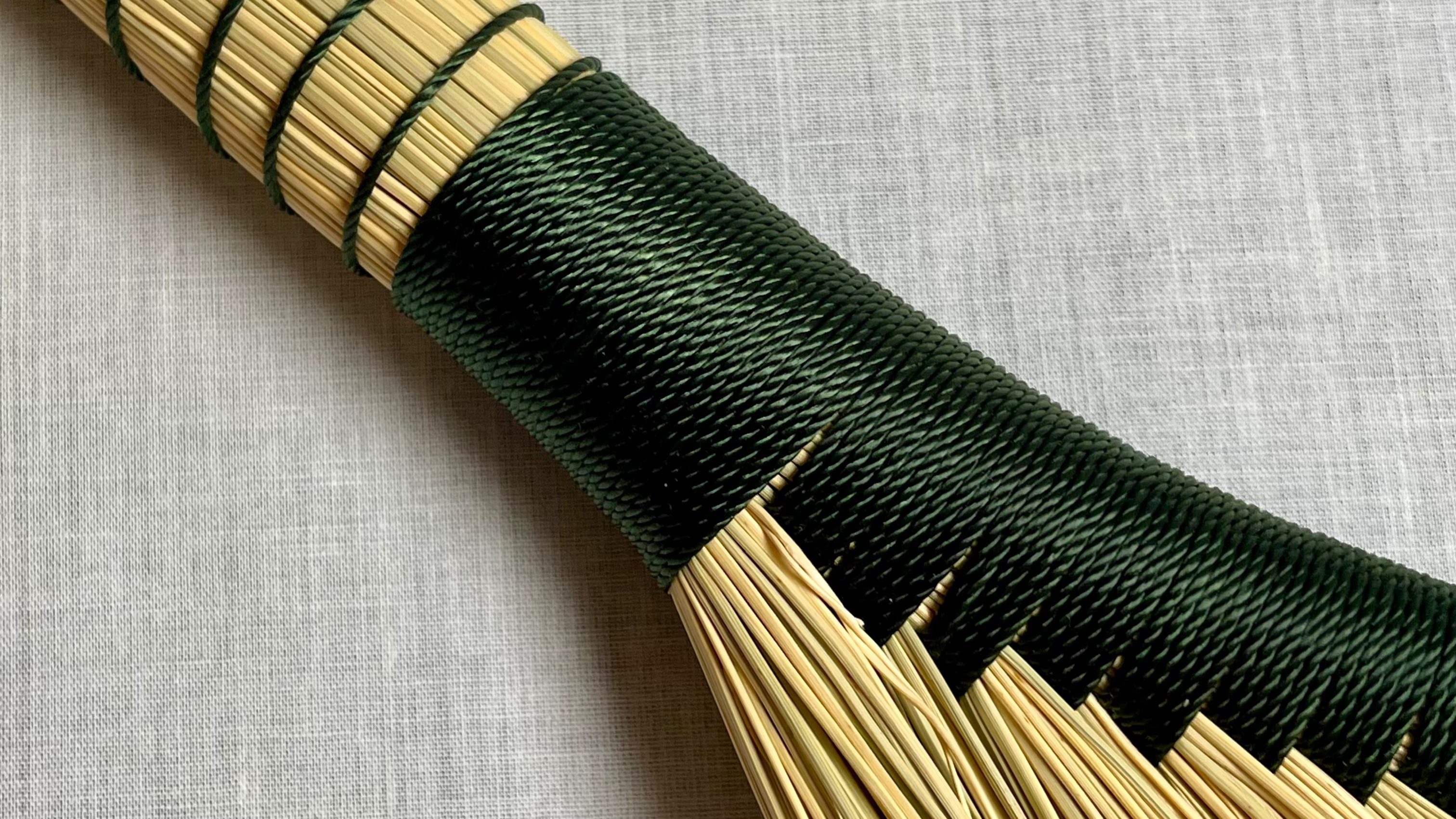 Bamboo broom with black handle on a light gray background