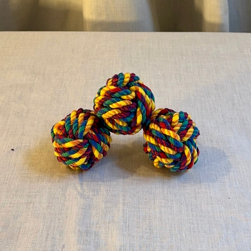Colorful knotted rope toy juggling ball on a light fabric surface